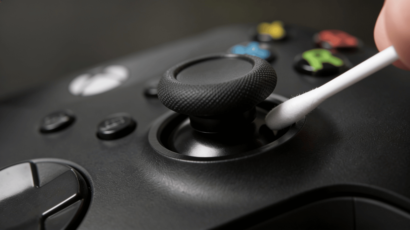 Cotton swab cleaning around base of xbox controller analog stick in close-up view