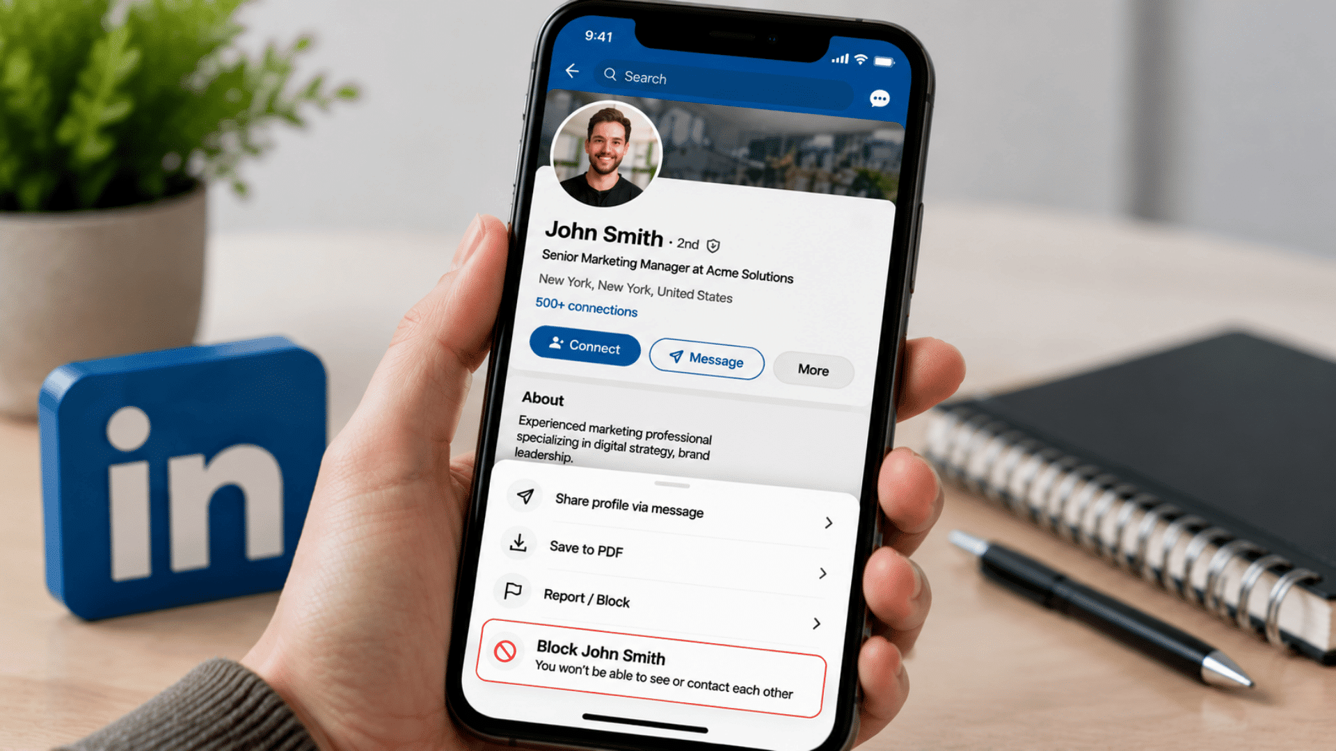 Hand holding smartphone showing LinkedIn profile John Smith with Report/Block menu and Block John Smith option highlighted