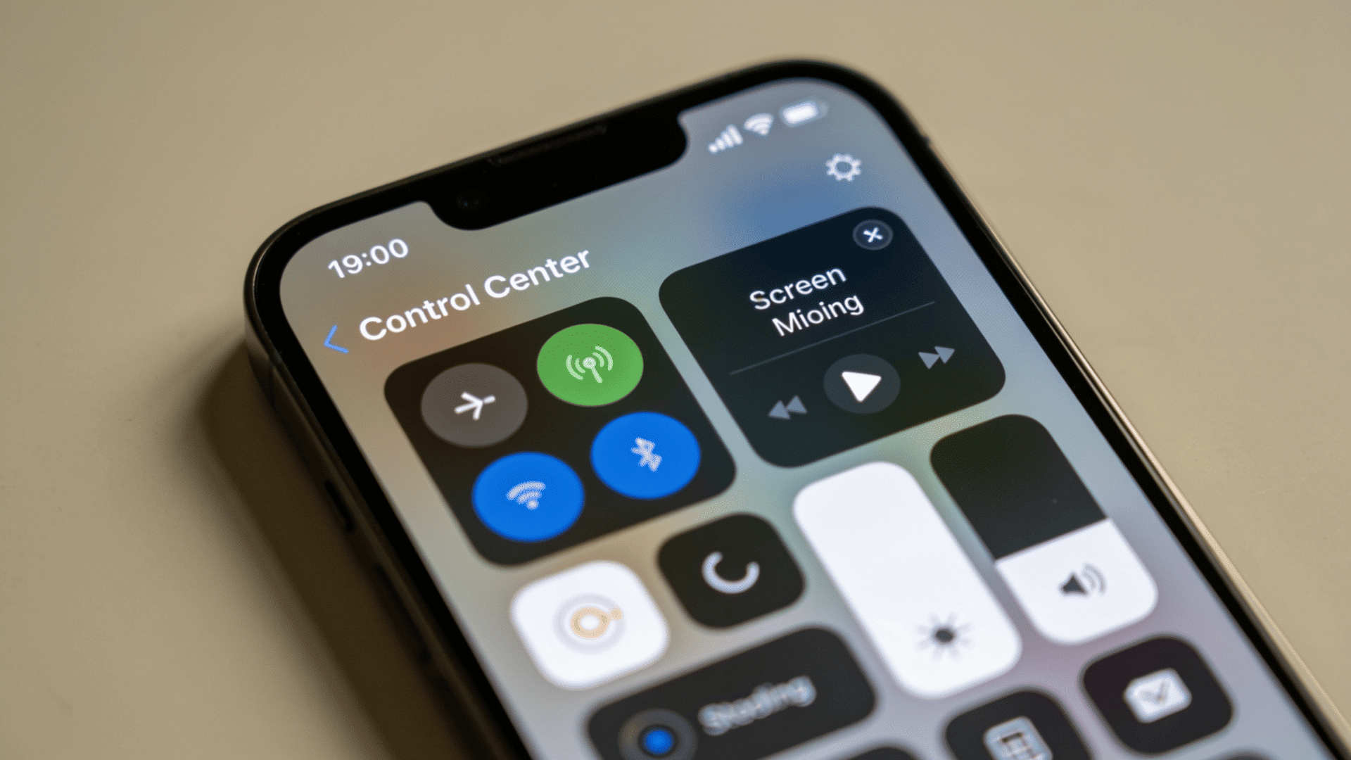 iPhone showing Control Center with quick toggles and screen mirroring icon visible