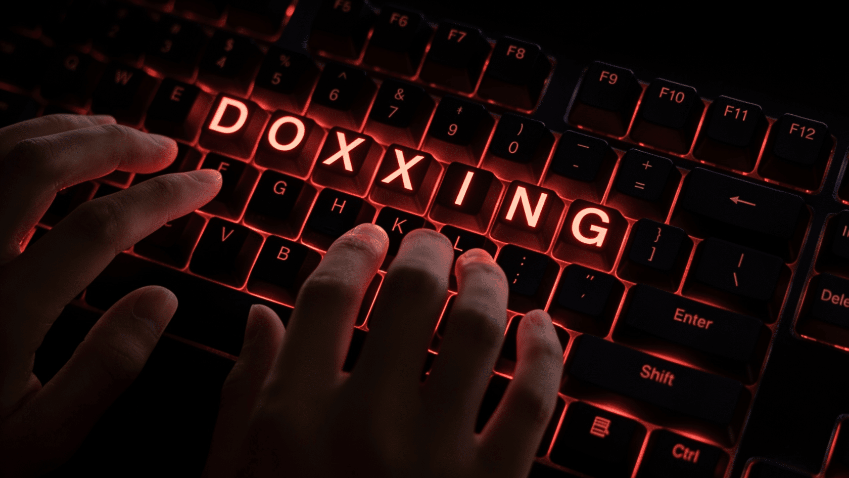 Doxxing concept showing a keyboard with glowing text and hands representing online data exposure threats.