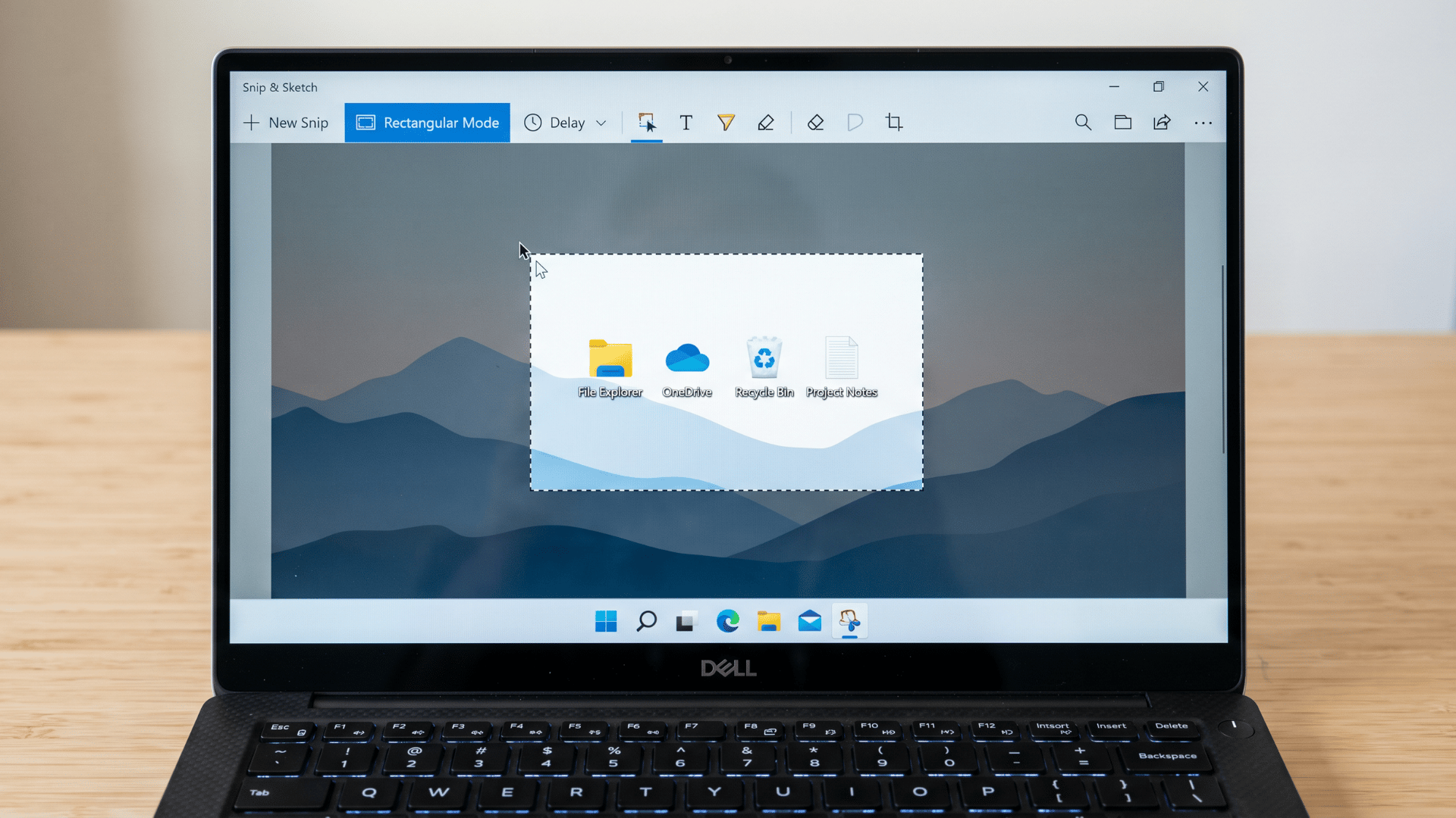 Laptop screen showing Snip & Sketch tool with selection box active over desktop interface
