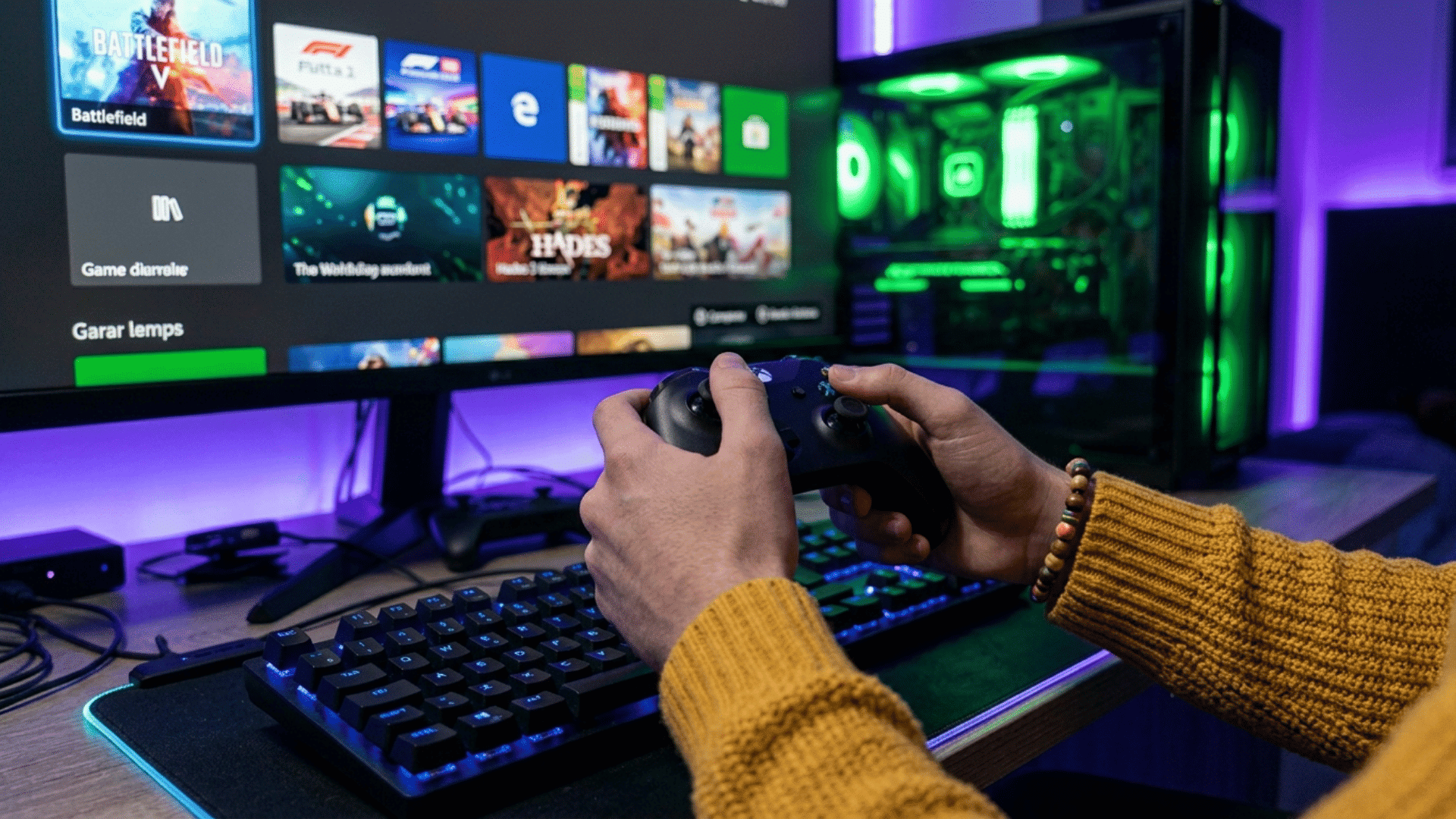 Person holding a game controller in front of a gaming monitor and desktop computer setup.