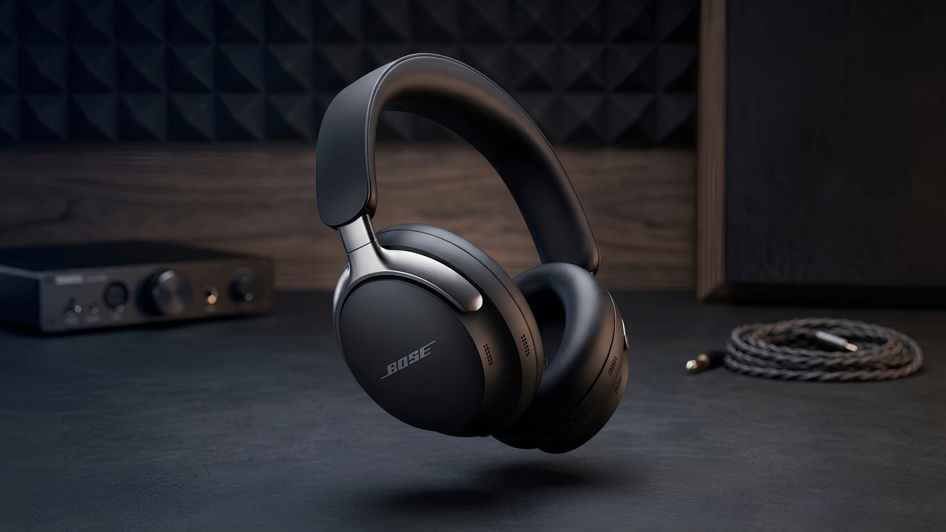 Black Bose QuietComfort Ultra over-ear headphones displayed beside an audio cable and amplifier.