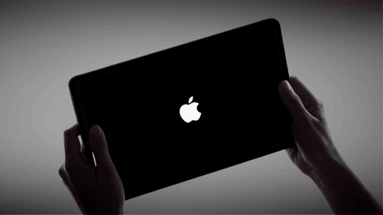 Hands holding an iPad with a black screen displaying the Apple logo during startup.