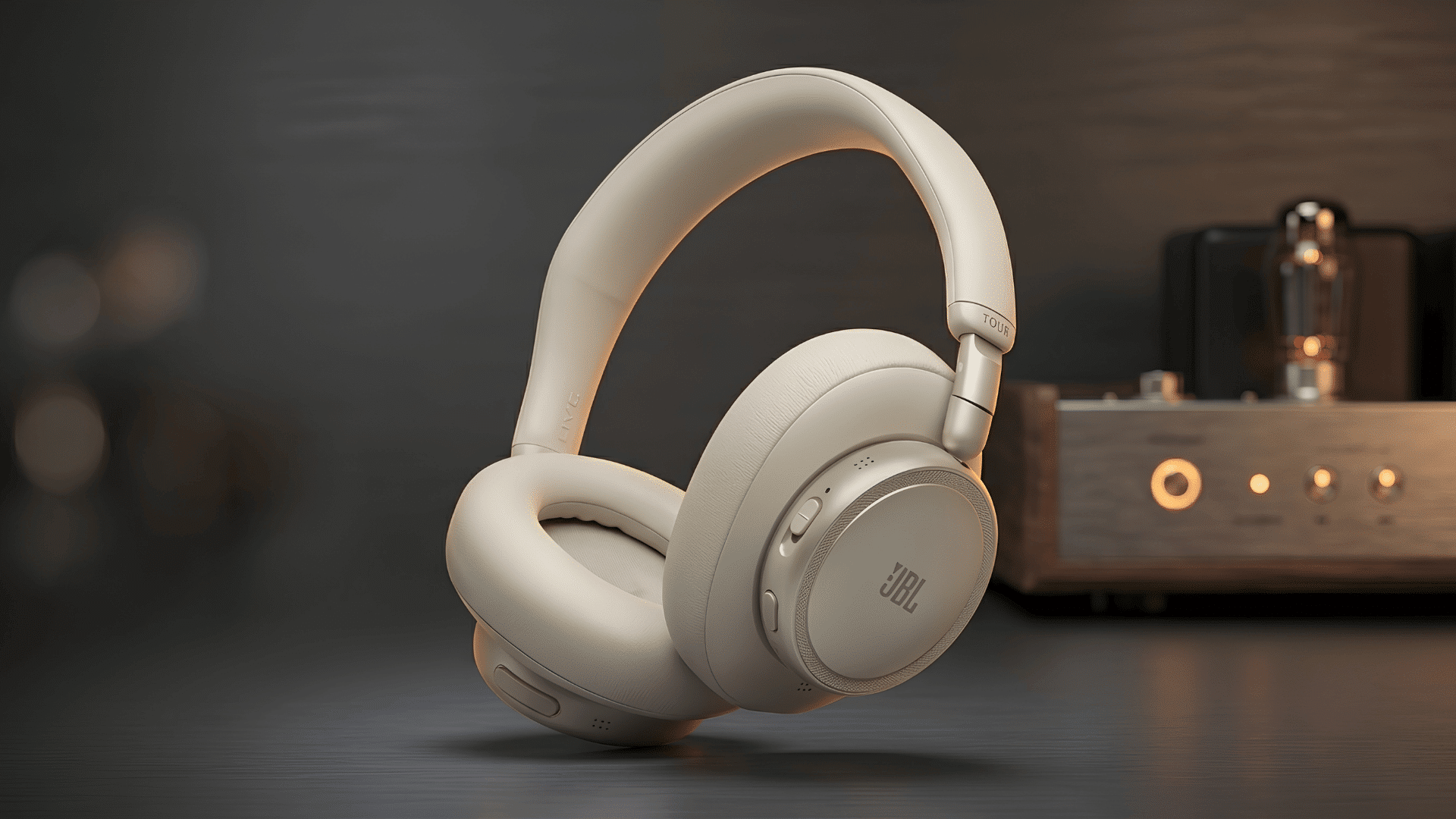 Cream JBL over-ear headphones displayed beside a softly lit audio amplifier.