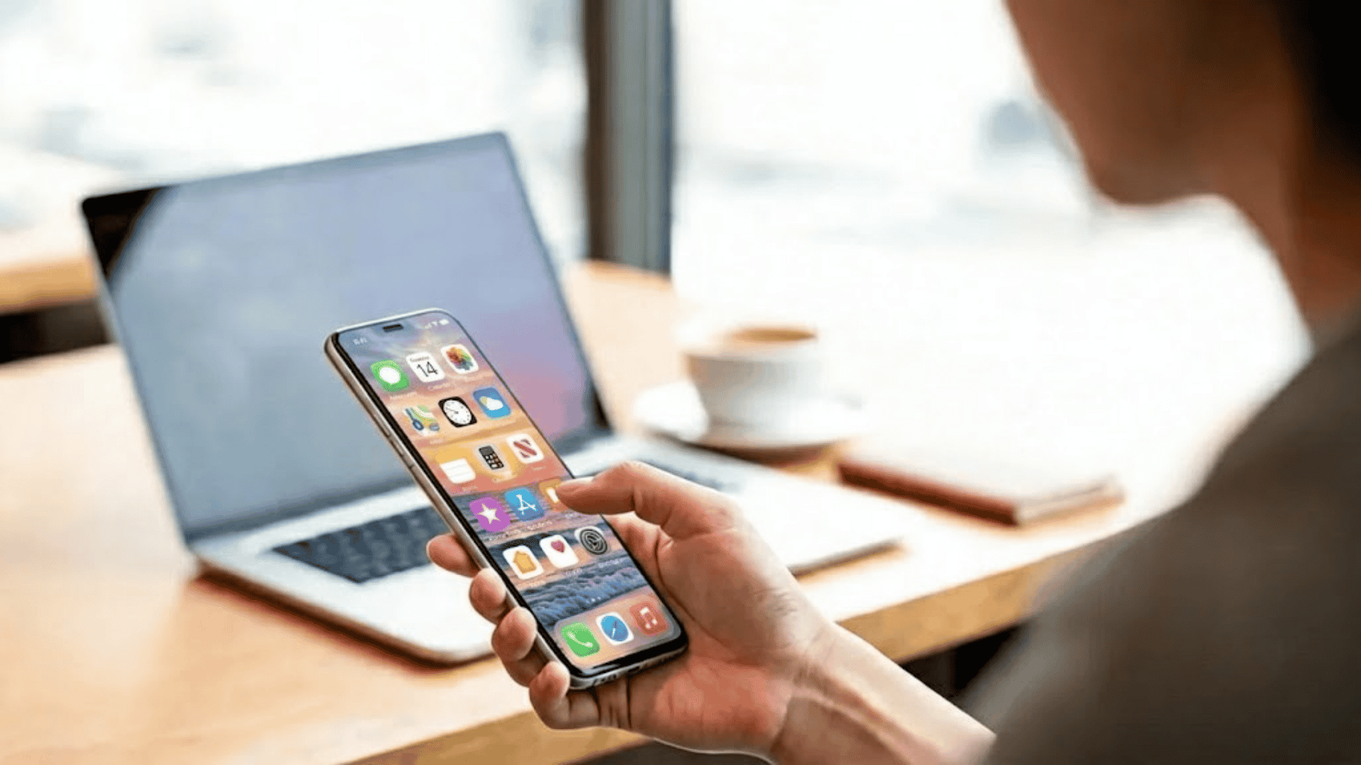 Person holding a slim smartphone while using it in a modern workspace.